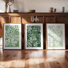 three framed art prints sitting on top of a wooden floor