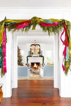 a living room filled with furniture and a fire place covered in christmas decorations on top of a hard wood floor