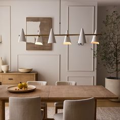 a dining room table with some fruit on it and lights hanging from the ceiling above