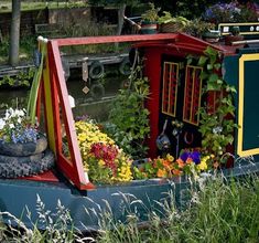 a boat is decorated with flowers and other things in the water's side yard