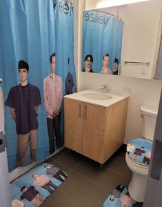 a bathroom with blue shower curtains and two men in pink shirts on the shower curtain