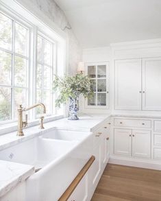 a kitchen with white cabinets and marble counter tops, gold faucets and brass handles