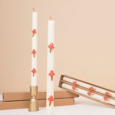 three candles with red bows on them sitting in front of two boxes and one candle