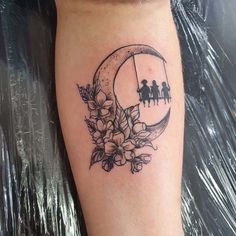 a woman's leg with flowers and people on the moon behind her is shown