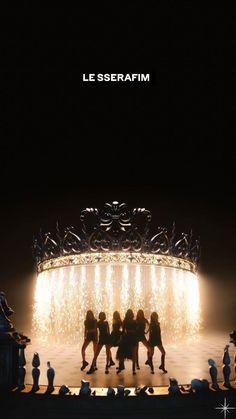 a group of people standing on top of a stage under a giant chandelier