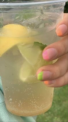 a woman's hand holding up a cup filled with lemonade and lime juice