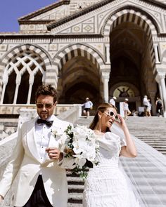 the bride and groom are walking down the stairs together in front of an ornate building