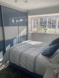 a bed sitting in a bedroom next to a window with blinds on the windowsill