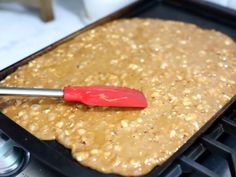 a red spatula is on top of a pan filled with oatmeal