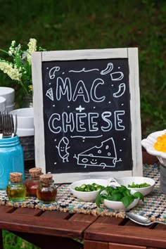 a table topped with lots of food next to a chalkboard sign that says mac and cheese