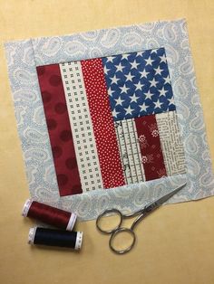 a pair of scissors sitting on top of a table next to an american flag quilt