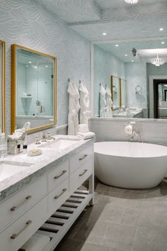 a bathroom with two sinks and a bathtub in the middle, surrounded by mirrors