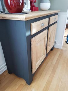 a kitchen island with two red vases on it's top and an apple sitting on top