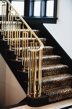 a set of stairs with leopard print carpet and gold handrails in front of a window