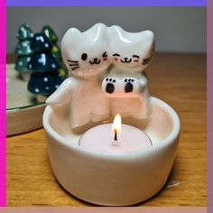 two cats sitting in a bowl with a candle