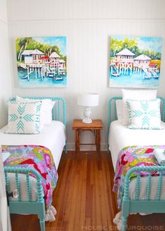 two twin beds in a room with wooden floors and paintings on the wall above them