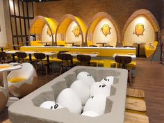 the interior of a restaurant with yellow tables and chairs, decorated with cartoon faces on them