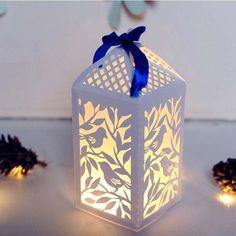 a lit candle holder sitting on top of a table next to pine cones and lights