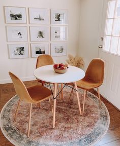 two chairs and a table in a room with pictures on the wall