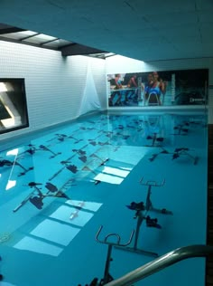 an indoor swimming pool with lots of water and equipment on the floor in front of it