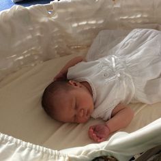 a baby is laying down in a crib with white sheets on it's sides