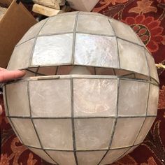 a person holding a light up in front of a white ball with squares on it