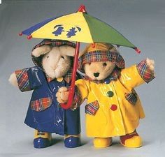 two teddy bears dressed in raincoats and holding an umbrella