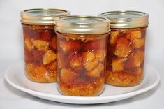 four jars filled with food sitting on top of a white plate