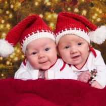 two babies are laying next to each other in front of a christmas tree