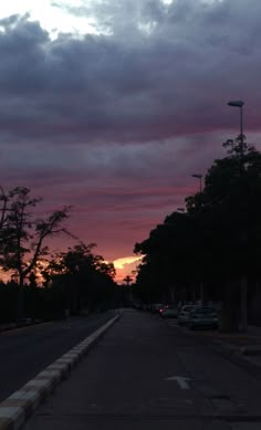 the sky is pink and purple as the sun sets in the distance behind some trees