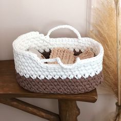 a crocheted basket sitting on top of a wooden table next to a plant