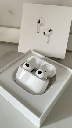 an apple airpods sitting in a box on top of a white table next to a card