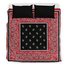 a red and black bed spread with two pillows on top of it, in front of a white wall