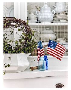 two american flags are placed on the counter next to some jars and vases with plants in them