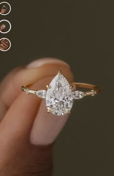 a woman's hand holding an engagement ring with three pear shaped diamonds