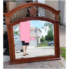 a mirror with a woman's reflection in it and a pink piece of paper sticking out of it