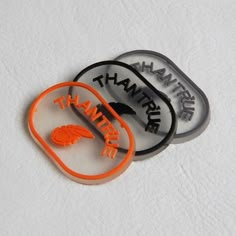 two orange and black hair clips sitting next to each other on a white table top