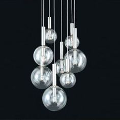 five clear glass balls hanging from a ceiling fixture with chrome rods and metal fittings