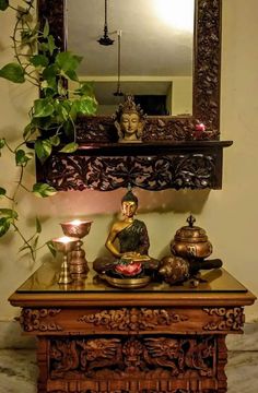 a buddha statue sitting on top of a wooden table next to a potted plant