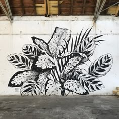 a large mural on the side of a building with leaves and plants painted on it