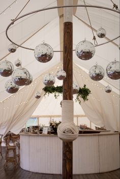 the inside of a tent decorated with hanging glass balls and rope, as well as potted plants