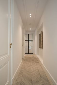 an empty hallway with white walls and wood flooring