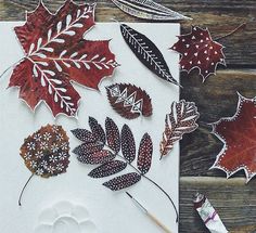 some leaves are laying on top of a piece of white paper and next to a brush