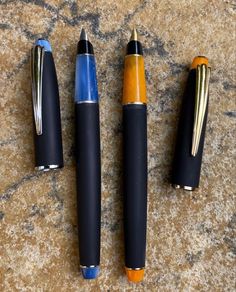 three different types of pens sitting on top of a stone floor next to each other