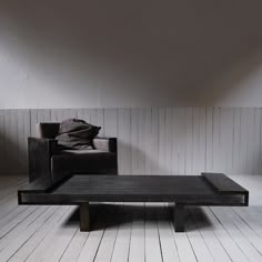 a black coffee table sitting on top of a hard wood floor next to a chair