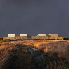 an image of a building that is in the middle of some brown grass and water