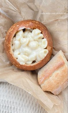 a bagel filled with macaroni and cheese sitting on top of wax paper