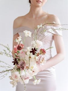 a woman in a dress holding a bouquet of flowers with her hands behind her back