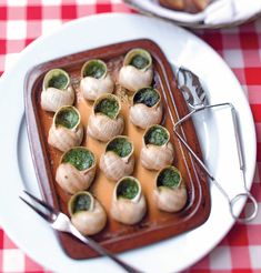 some food is sitting on a white plate and red checkered tablecloth with silverware