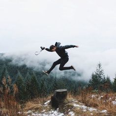 a man jumping in the air with a tennis racquet on top of a mountain